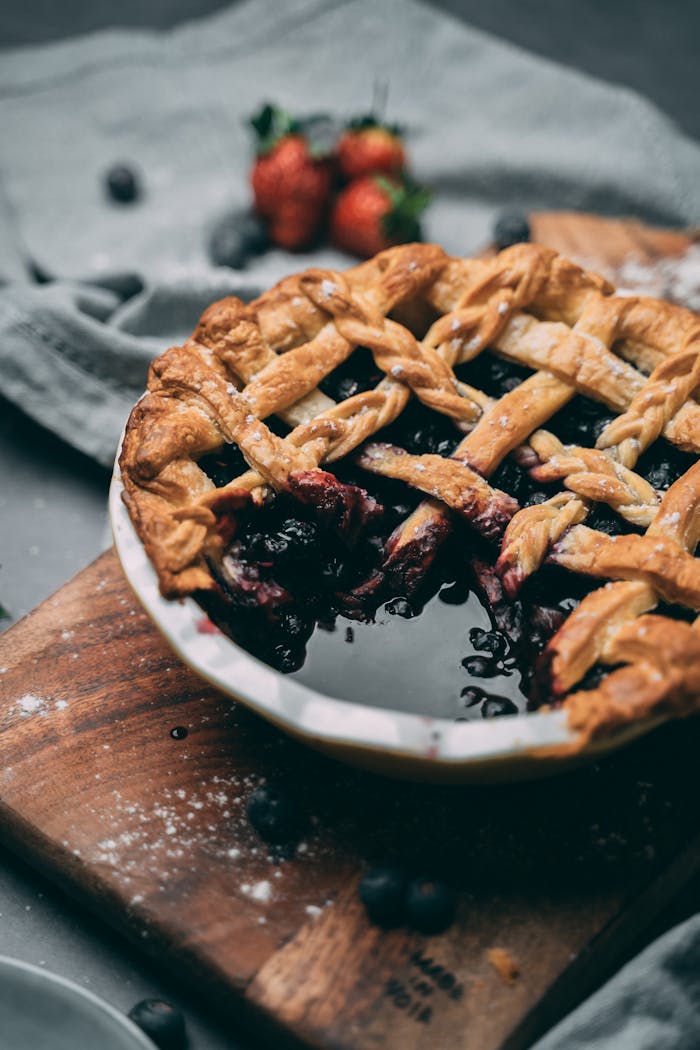 home-img A delicious homemade berry pie with a lattice crust on a wooden board, captured in rustic style.